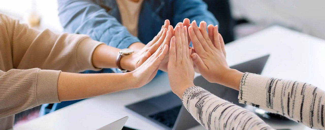 Hände einer Gruppe geben sich ein High-Five
