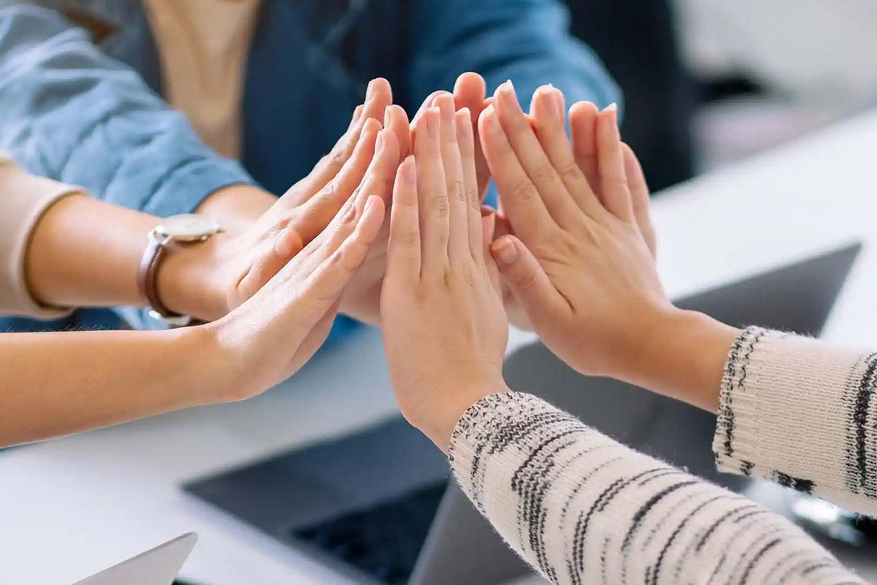 Hände einer Gruppe geben sich ein High-Five