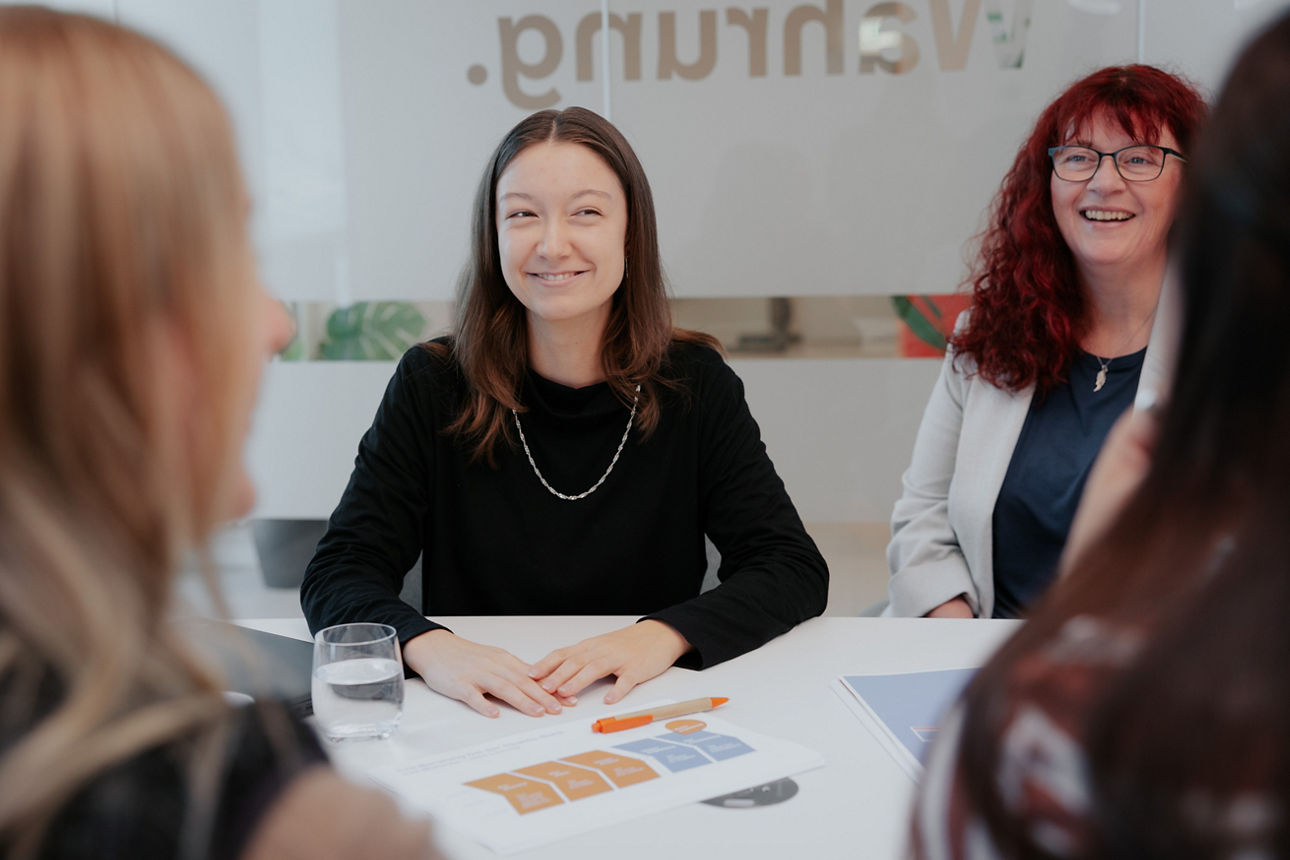 4 Frauen an einem Tisch mit Papier darauf