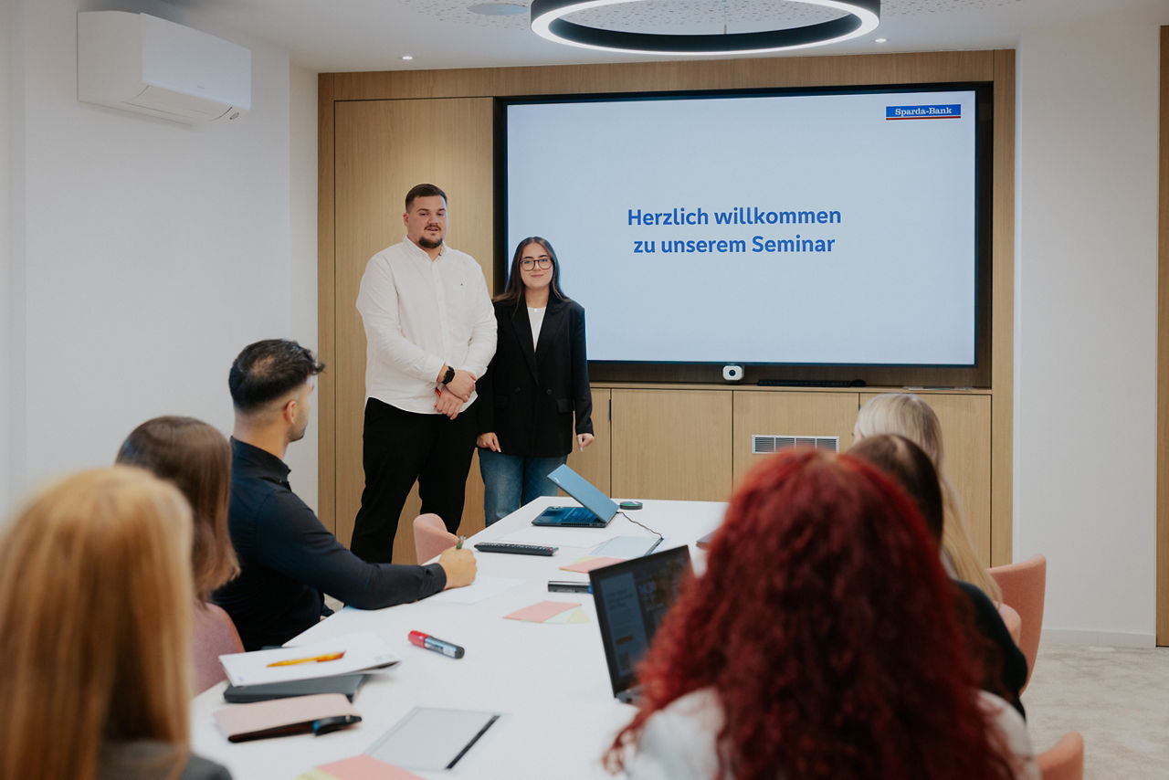 mehrere Personen gucken auf Präsentation in einem Seminar Raum