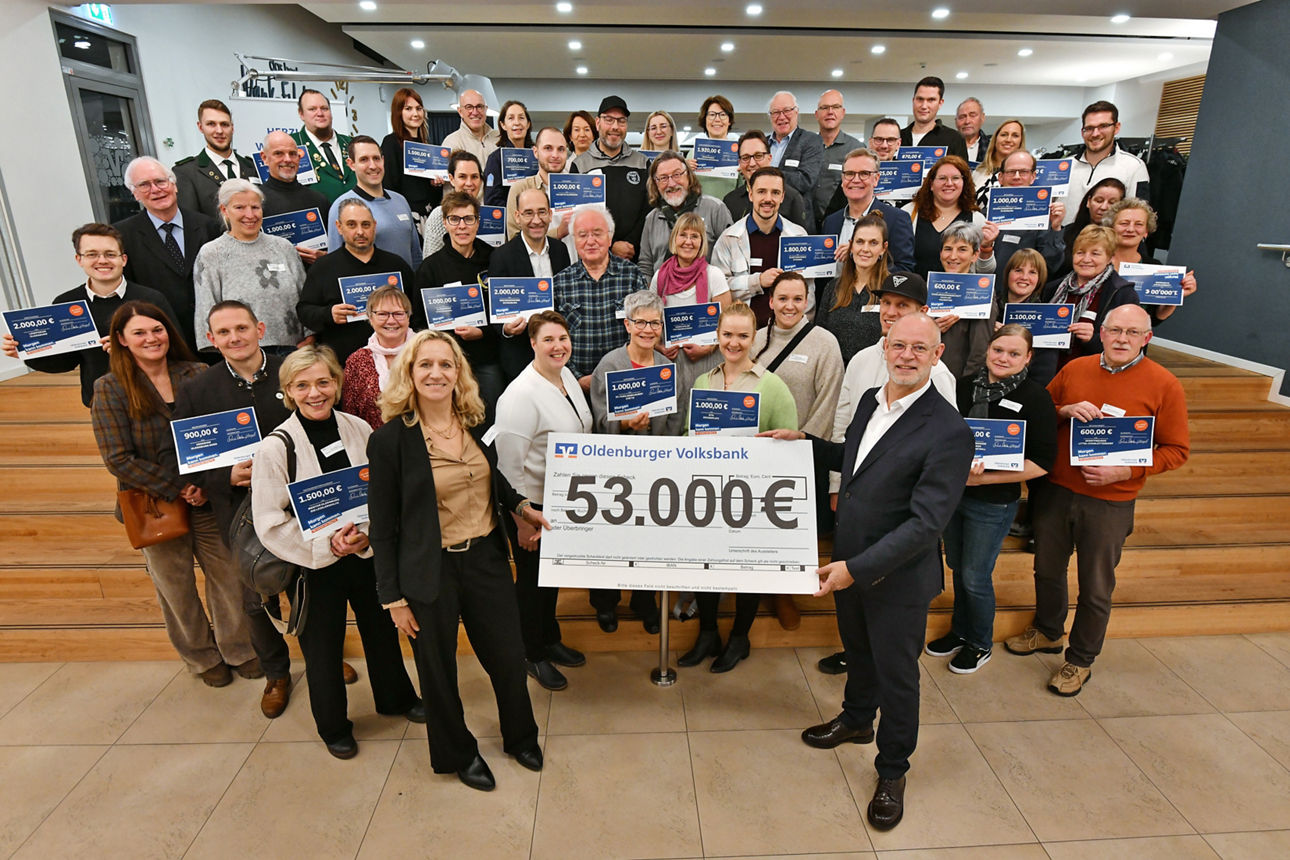 Vertreterinnen und Vertreter Oldenburger Vereine posieren mit einem symbolischen Scheck