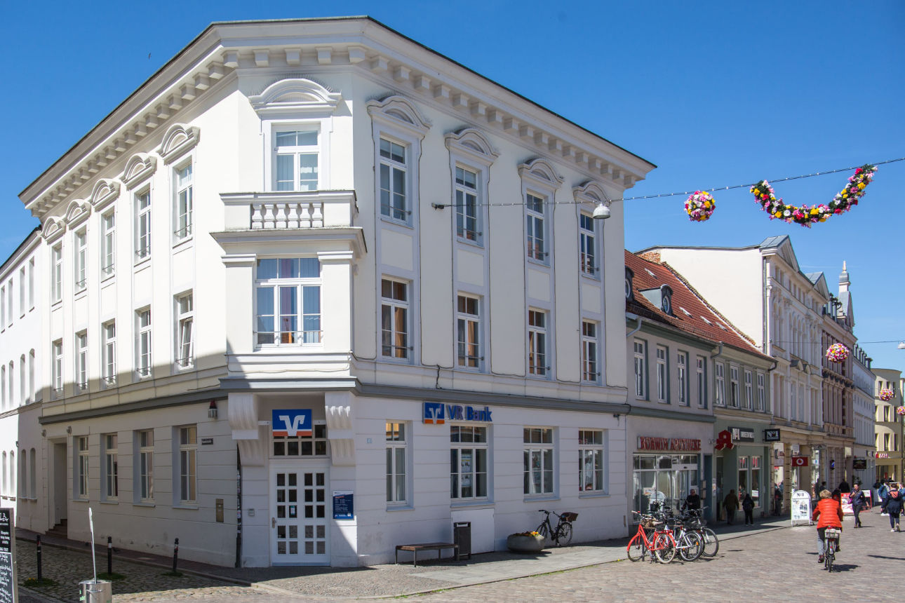 Ein weißes Eckhaus mit drei Etagen der VR Bank Mecklenburg eG in Güstrow