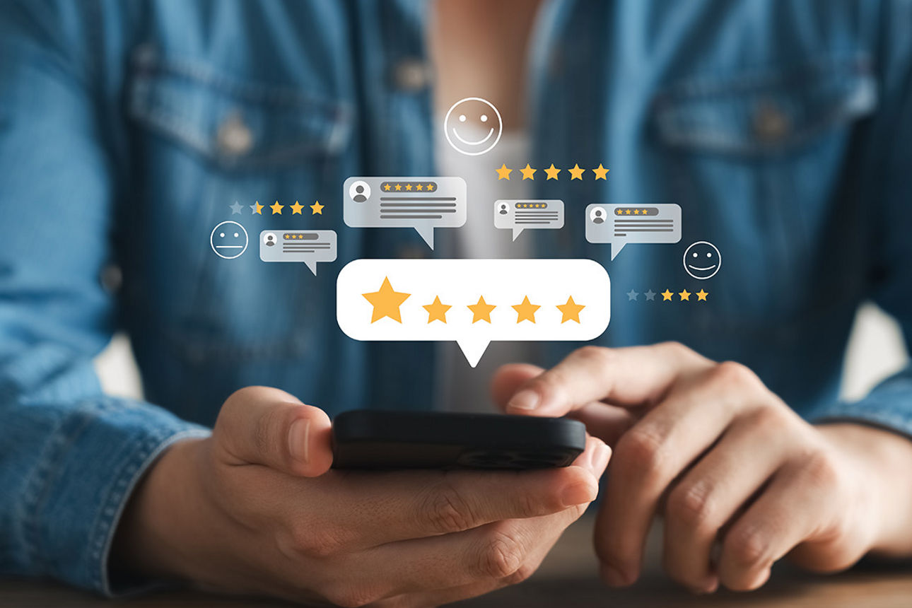 Mensch sitzt am Handy und über den Handy sind 5 Sterne Bewertungen
