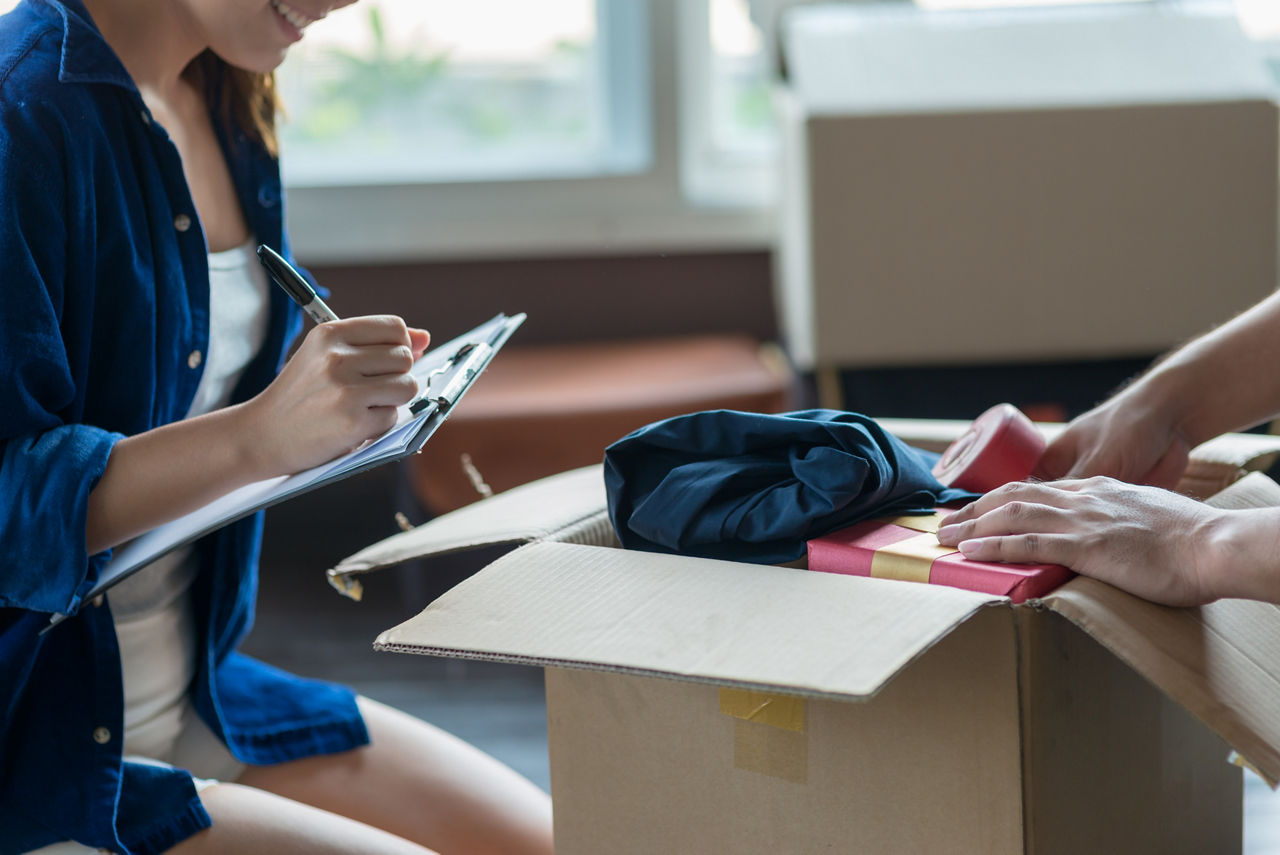 Zwei Menschen stehen an einem gepackten Umzugskaton 