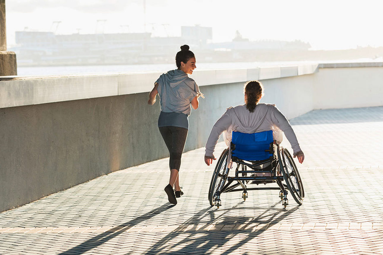 Joggerin neben Rollstuhlfahrerin