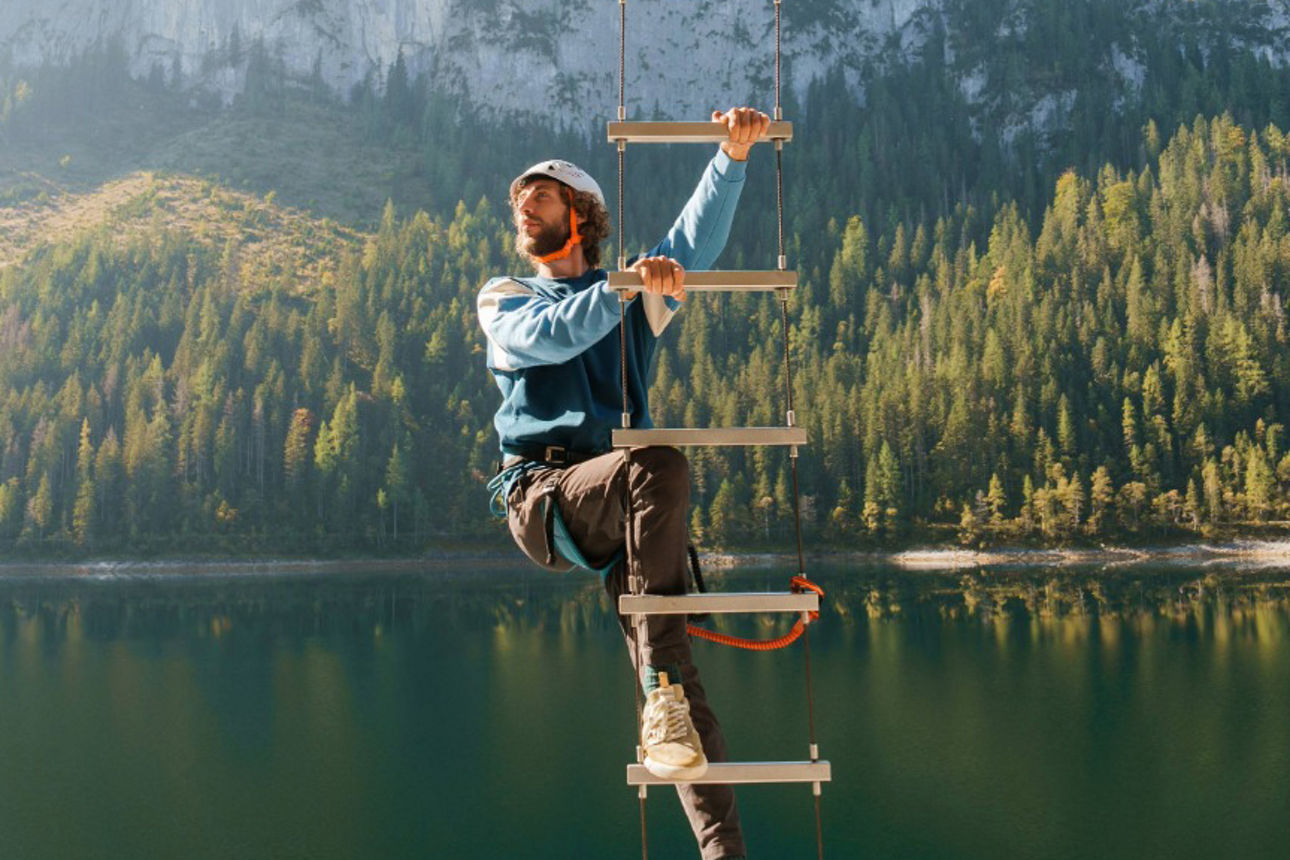 Mann mit Helm klettert auf einer hohen Leiter