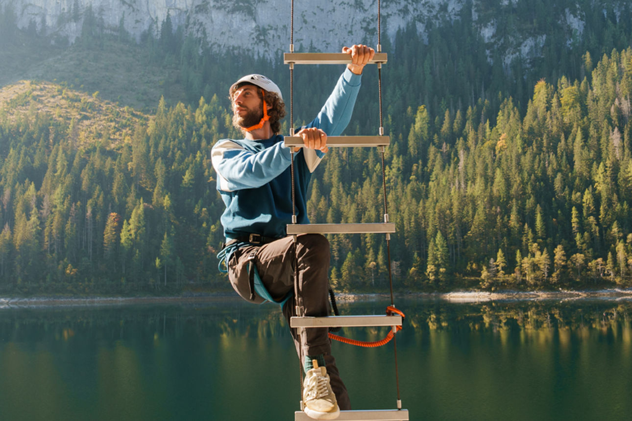 Mann mit Helm klettert auf einer hohen Leiter