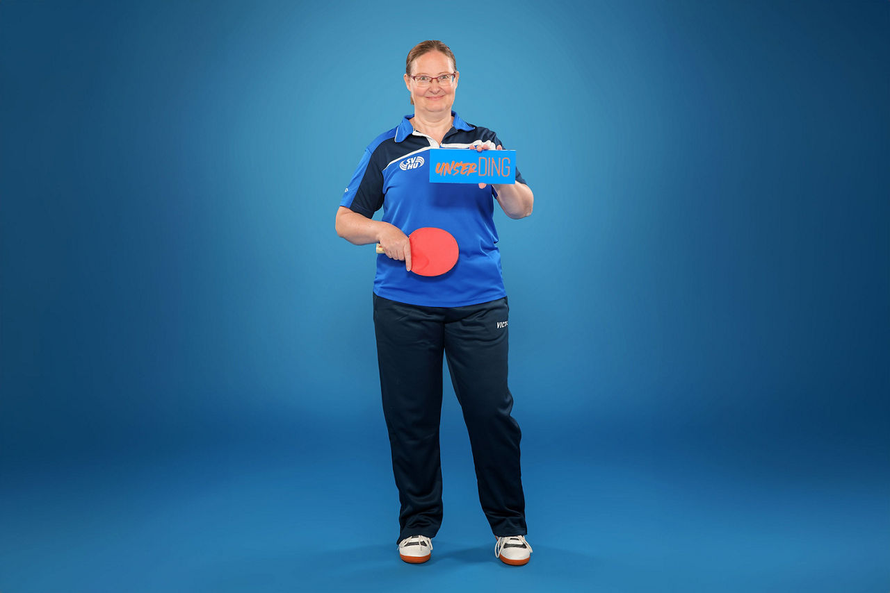 Unsere Kollegin Katrin im Sportoutfit mit Tischtennisschläger und unserDING-Schild in der Hand