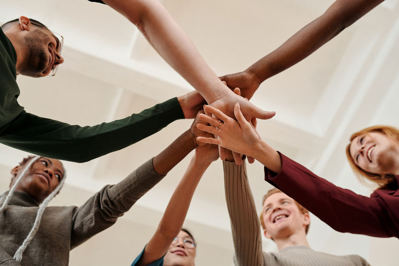 Menschen stehen im Kreis und halten ihre Hände zusammen