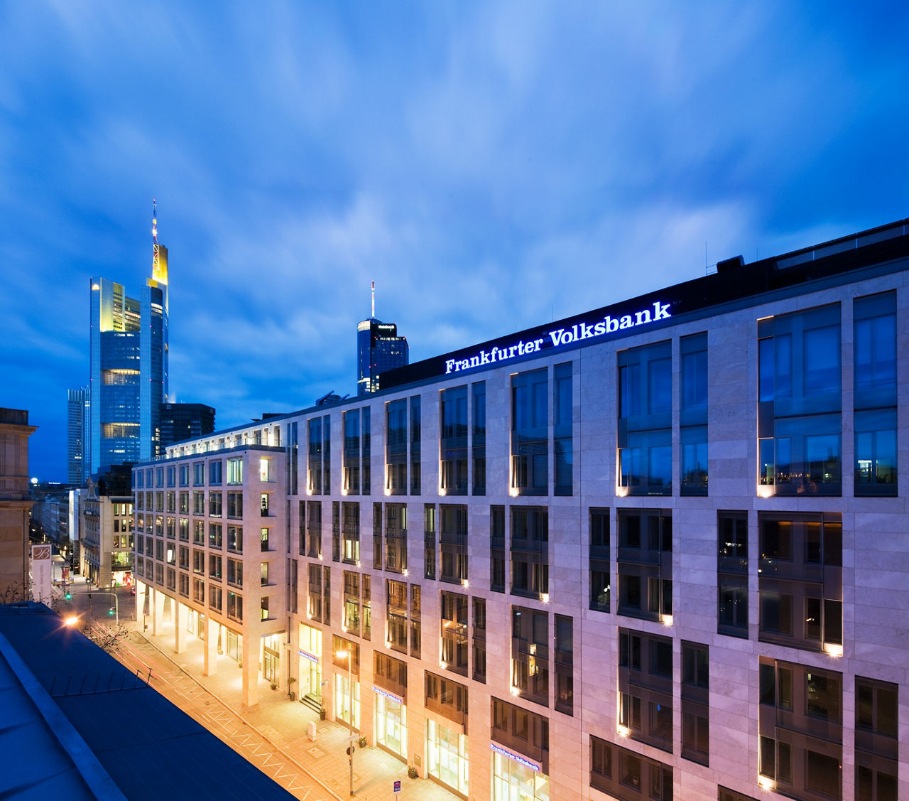 Gebäude der Frankfurter Volksbank am Abend mit der Skyline im Hintergrund