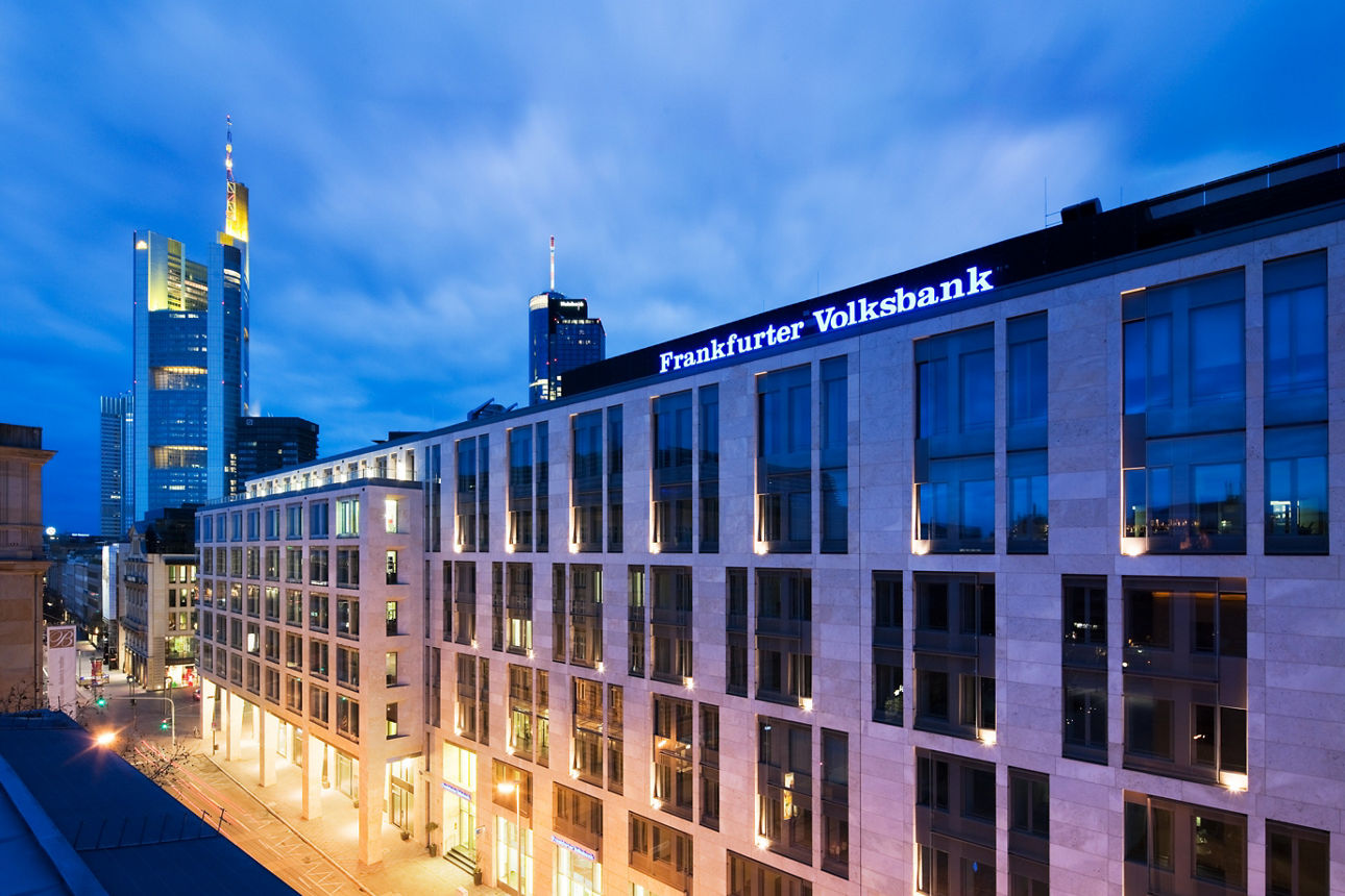 Gebäude der Frankfurter Volksbank am Abend mit der Skyline im Hintergrund