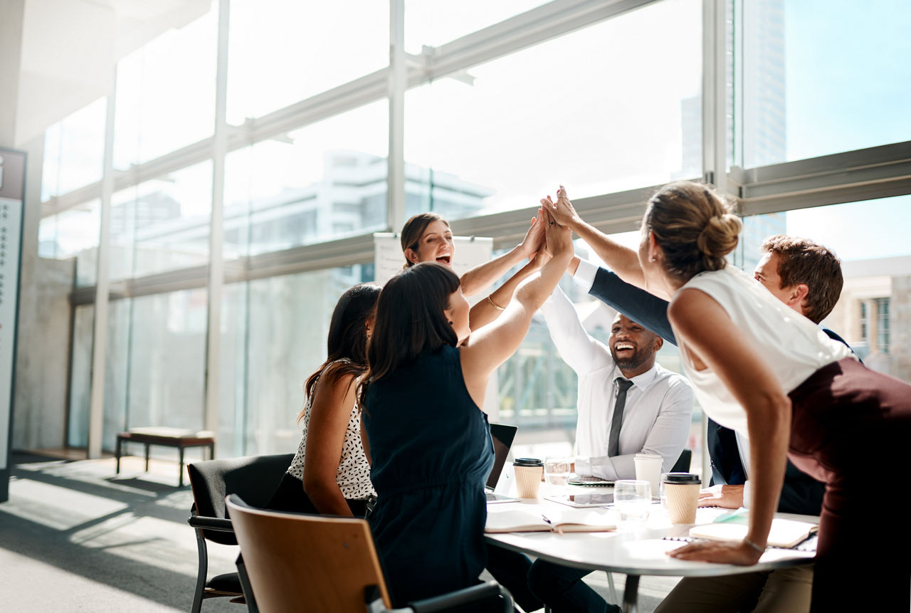 Ein Team klatscht sich gleichzeitig mit den Händen im Büro ab