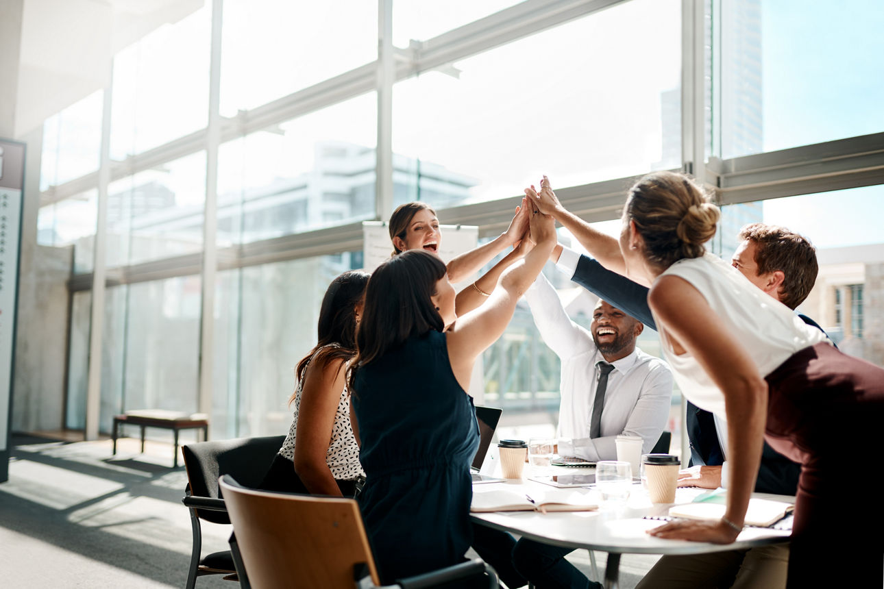 Ein Team klatscht sich gleichzeitig mit den Händen im Büro ab