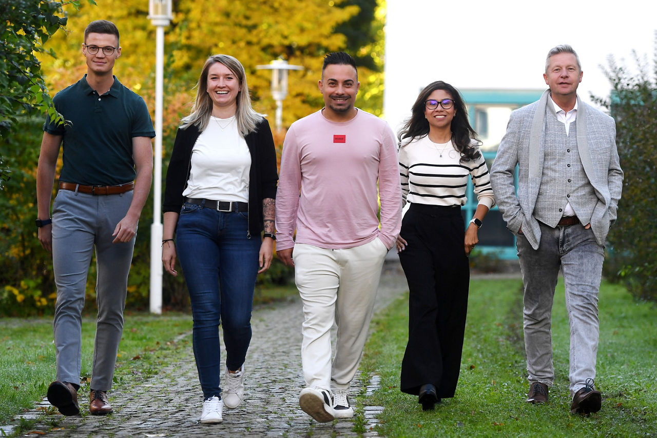 Eine Gruppe von fünf Erwachsenen, davon zwei Frauen und drei Männer laufen im freien und lachend auf den Kameramann zu. Eine Gruppe von fünf Erwachsenen, davon zwei Frauen und drei Männer laufen im freien und lachend auf den Kameramann zu.