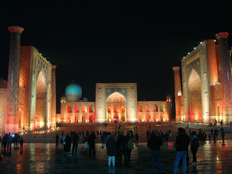 Der Registan-Platz in Samarkand, Usbekistan, leuchtet im nächtlichen Himmel. Architektonische Details werden durch warmes Lic
