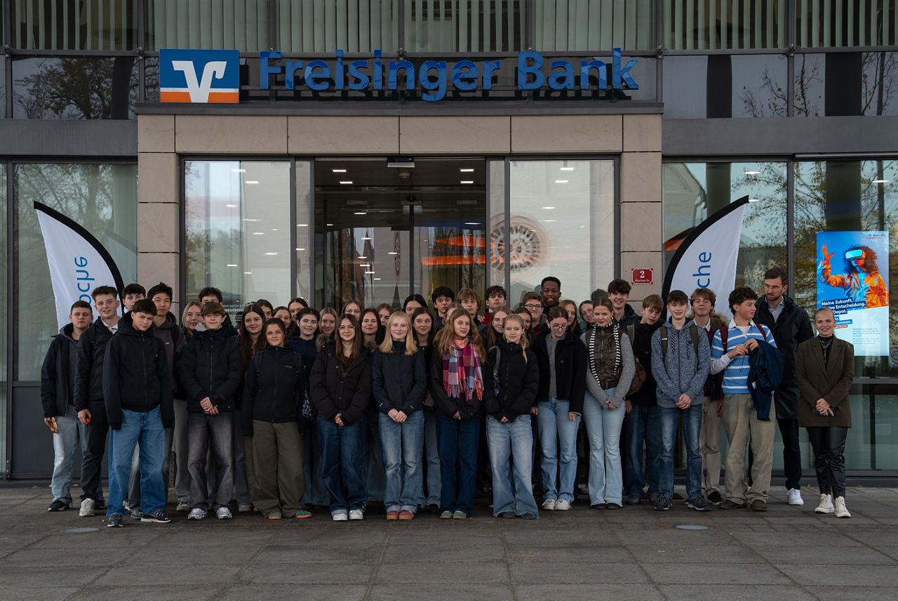 Gruppenfoto vor Eingang Freisinger Bank von Schüler/innen, Lehrer Tobias Drexler und Alena Gula (Freisinger Bank)