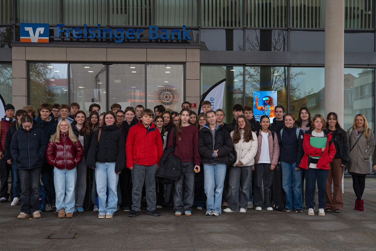 Gruppenfoto der Schüler/innen vor dem Eingang der Freisinger Bank mit Lehrerin und Alena Gula (Freisinger Bank)