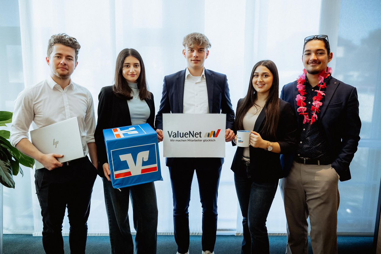 Gruppe junger Erwachsener präsentiert ValueNet-Box und Gutscheine im Büro.
