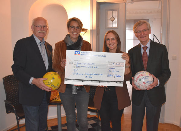 Zwei Männer halten einen Ball, zwei Frauen einen Spendenscheck.