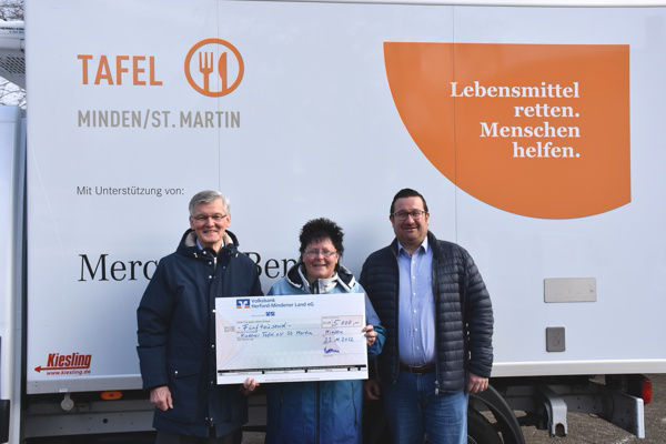 Drei Personen mit Spendenscheck vor einem LKW der Mindener Tafel.