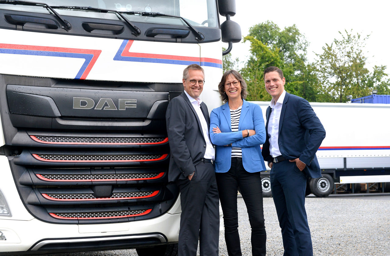 Zwei Männer und eine Frau vor LKW