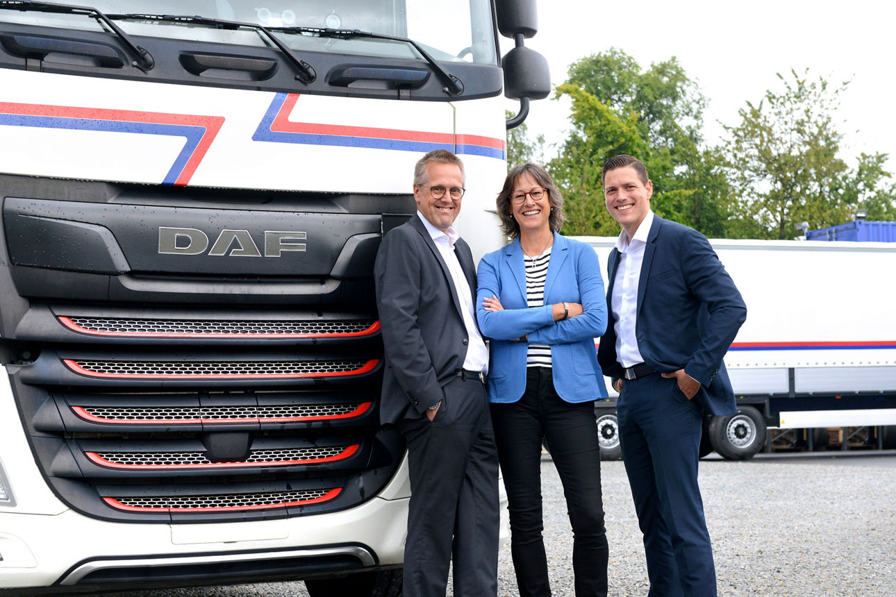 Zwei Männer und eine Frau vor LKW