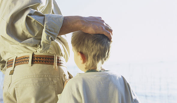 Vater hält Hand über Kopf vom Sohn