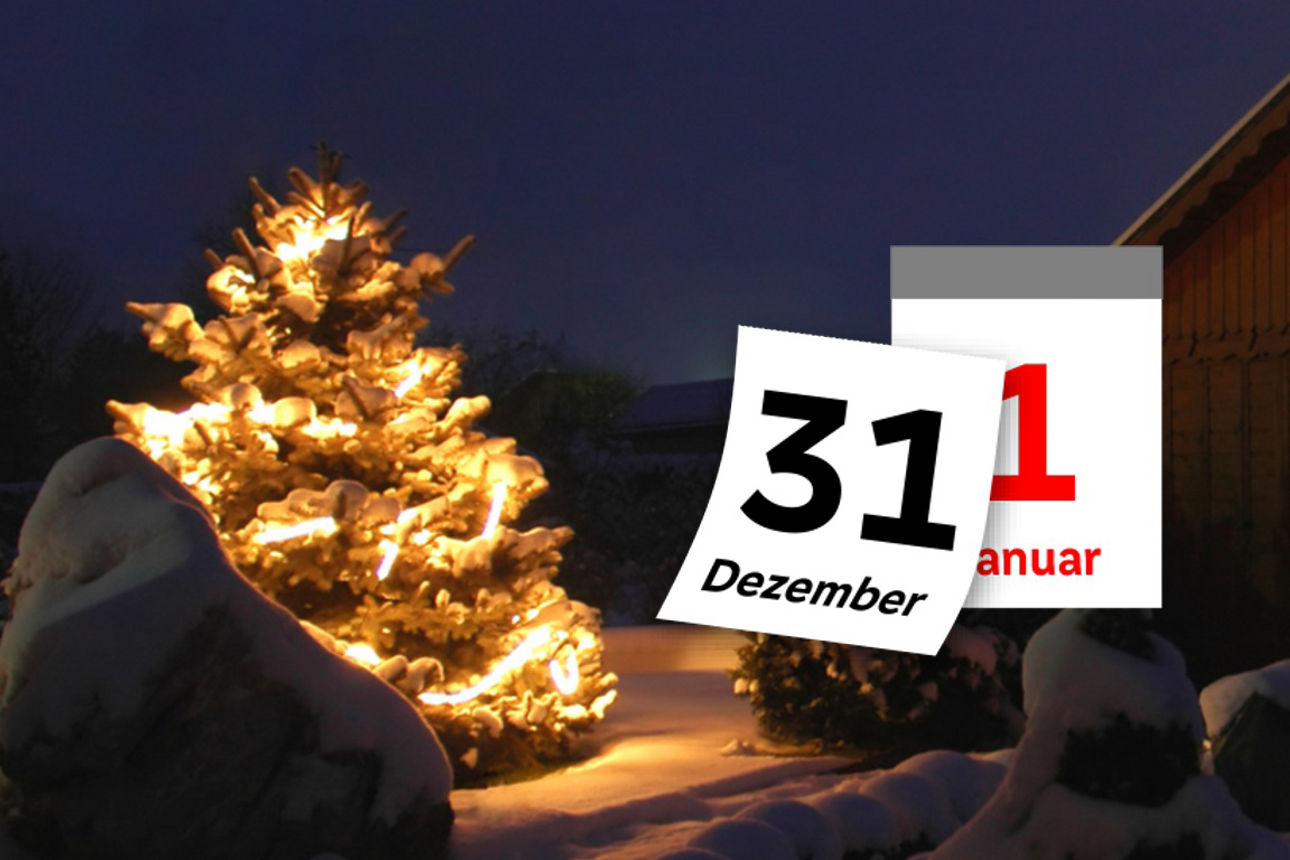 Abreißkalender vom 31. Dezember auf den 1. Januar vor einem weihnachtlichen Hintergrund