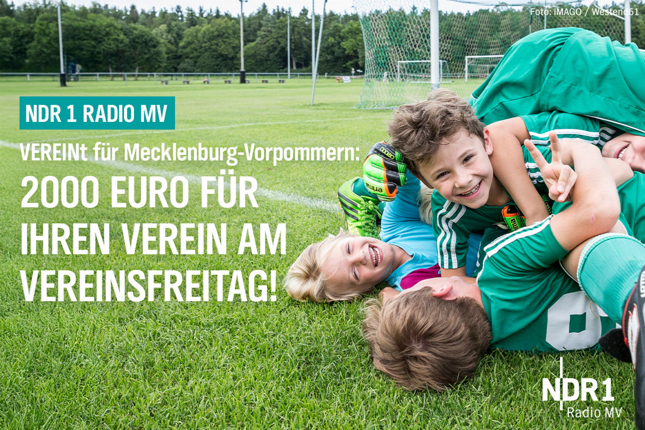 Kinder liegen als Gruppe auf dem Fußballfeld und freuen sich.