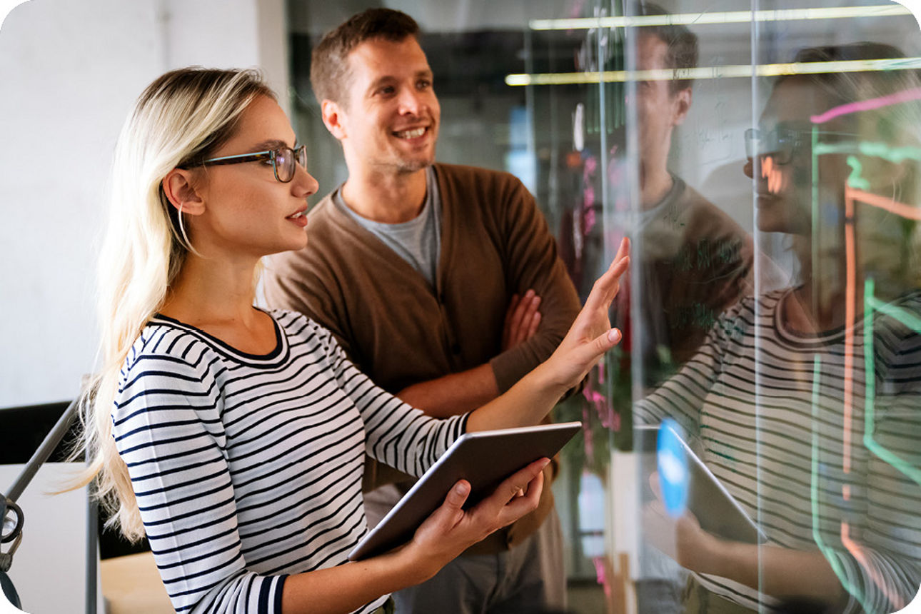 Zwei junge Menschen stehen planend vor einem Bildschirm