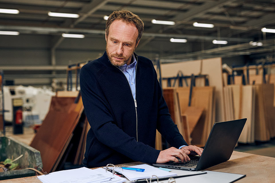 Ein Mann arbeitet in einer Werkstatt an einem Laptop