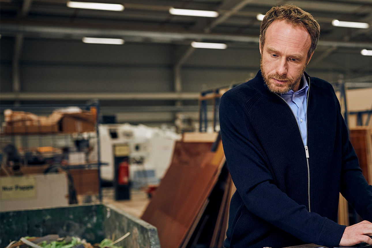 Unternehmer in der Betriebshalle am Laptop