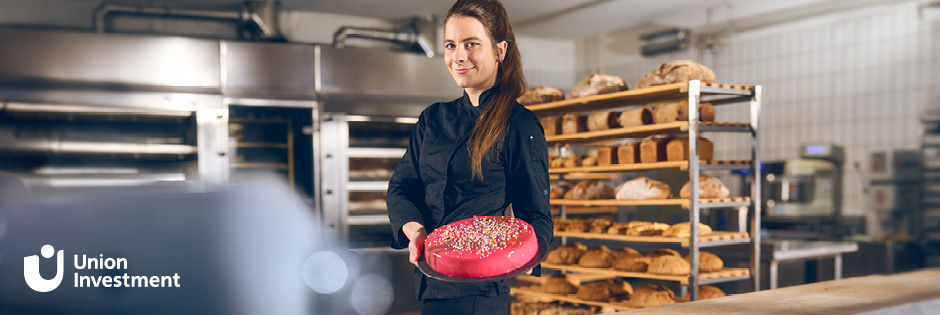 Bäckerin mit pinkem Kuchen in einer Bäckerei