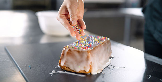 Eine Person, die eine Schicht Zuckerguss auf einen Kuchen aufträgt