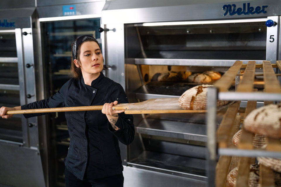 Frau schiebt Brot in den Ofen