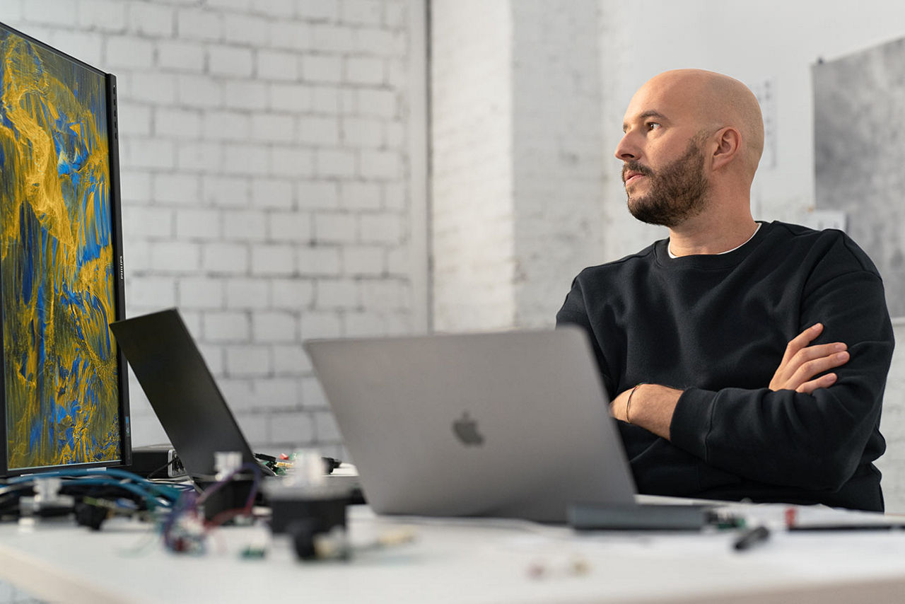 Mann sitzt mit verschränkten Armen vor seinem Laptop