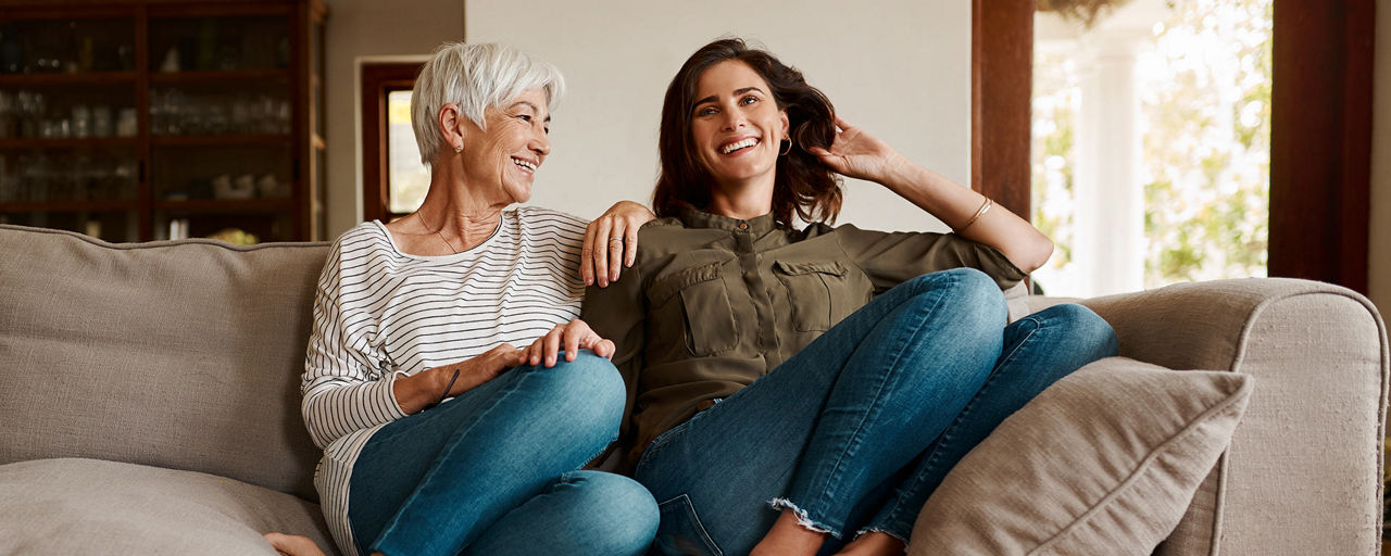 Frauen zweier Generationen sitzen lachend auf einem Sofa