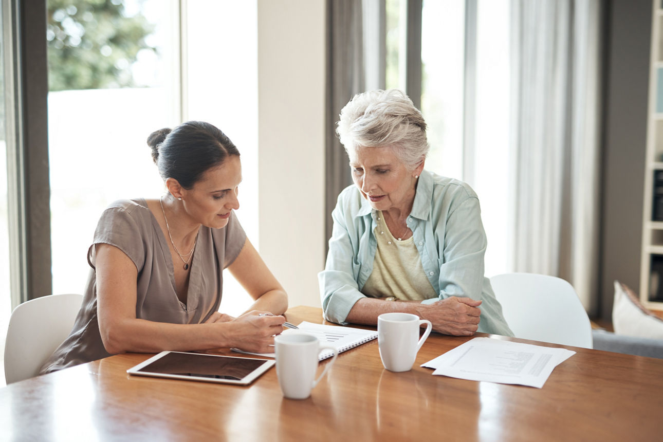 Eine jüngere und eine ältere Frau sitzen gemeinsam am Tisch und besprechen ihre Finanzen
