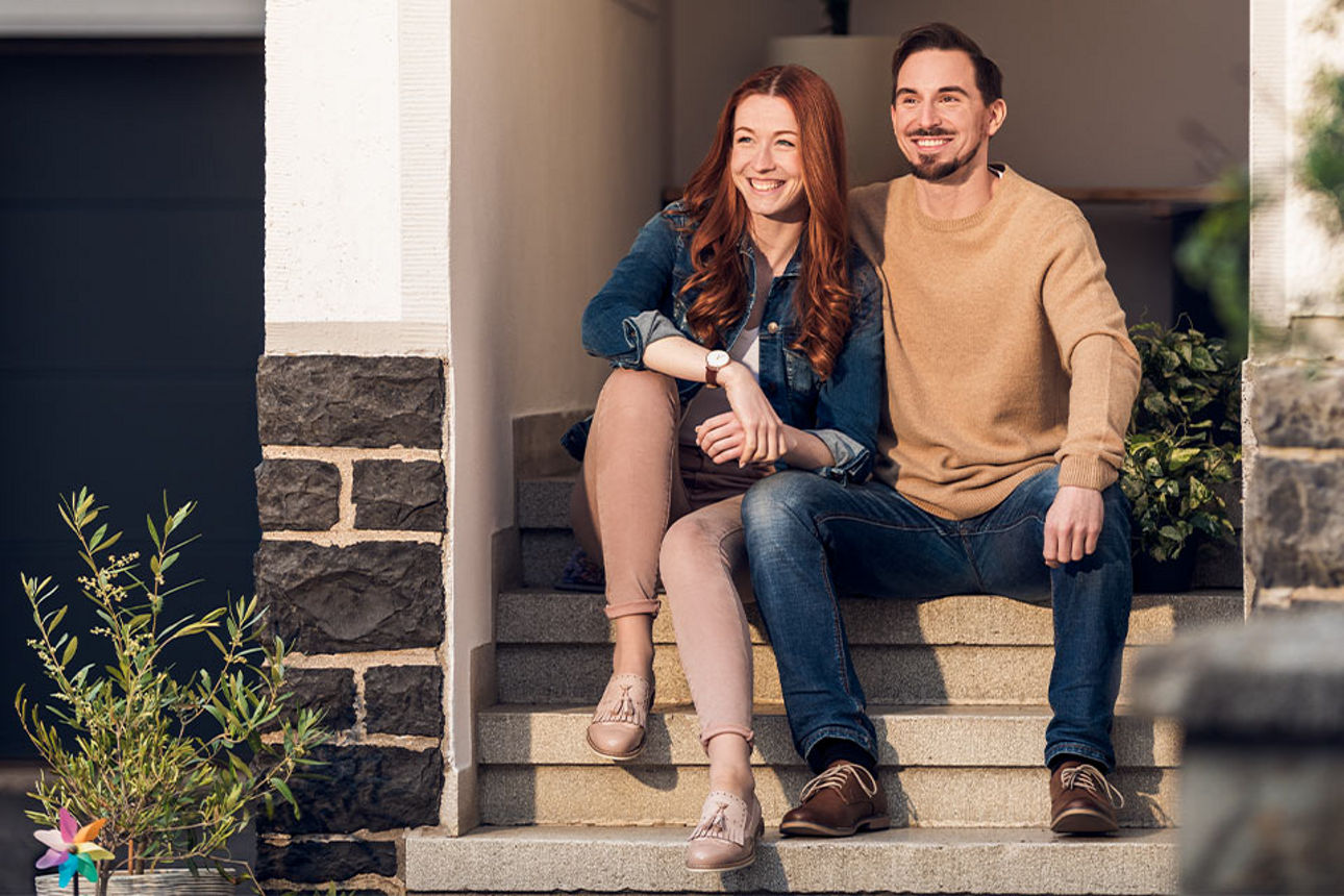 Eine Frau und ein Mann sitzen auf einer Treppe vor einem Haus