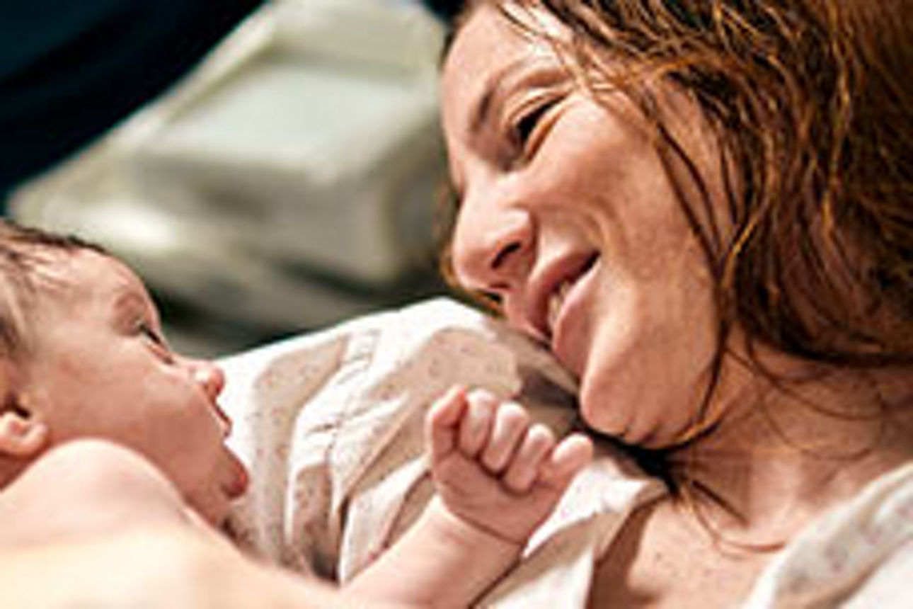 Zwei Teenager sitzen in einem Bus, die Köpfe aneinandergelehnt, während sie sich einen Witz erzählen.