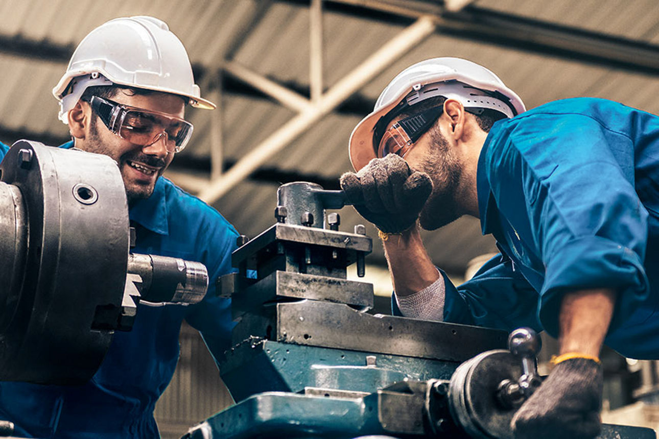 Zwei Arbeiter bedienen eine Industrieanlage