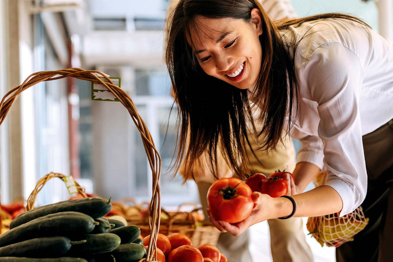Frau schaut sich Tomaten in einem Obst-/Gemüseladen an