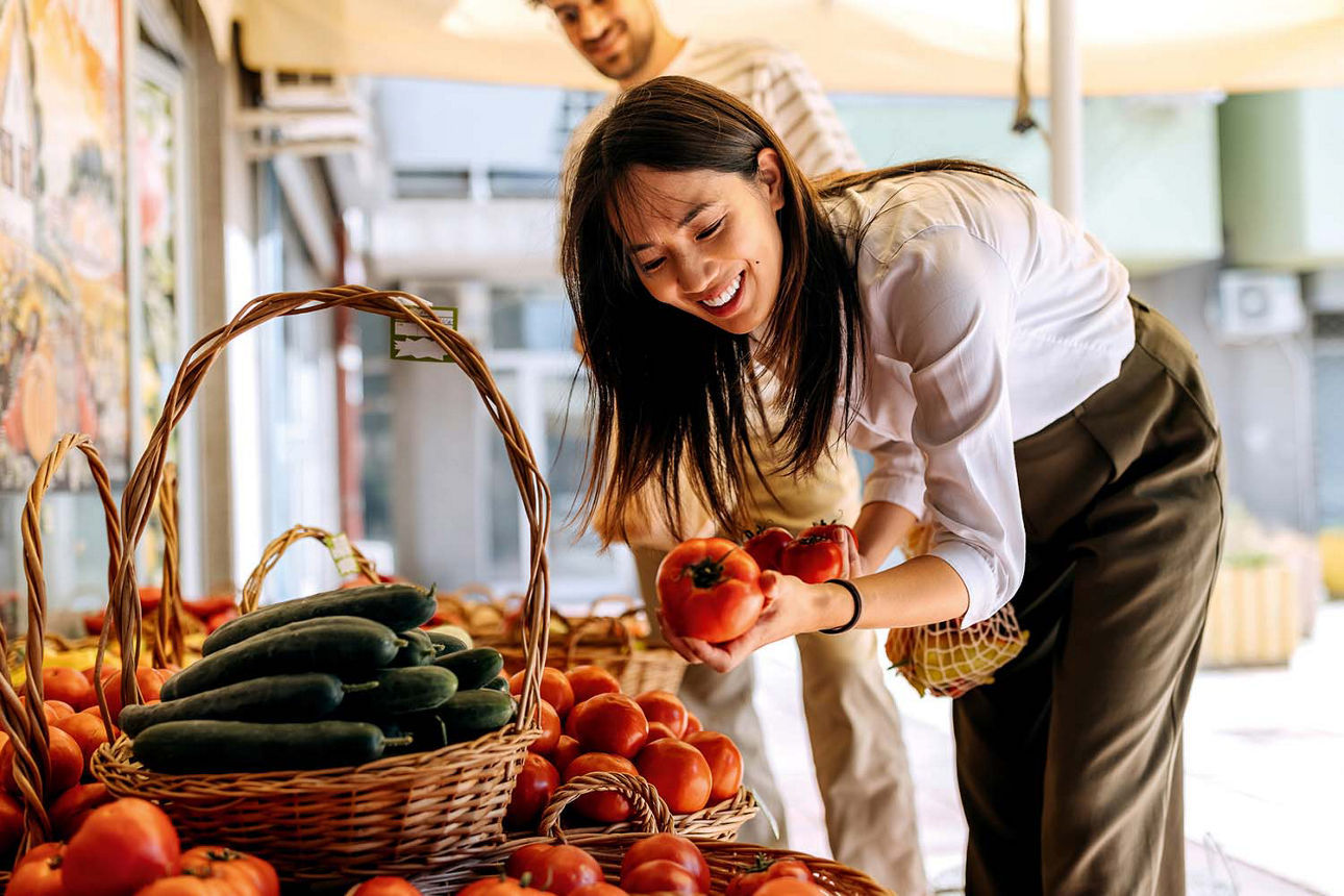 Frau die Tomaten im Obstladen anschaut