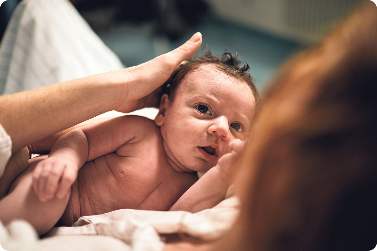 Eine Mutter hält ihr neugeborenes Baby in der Hand