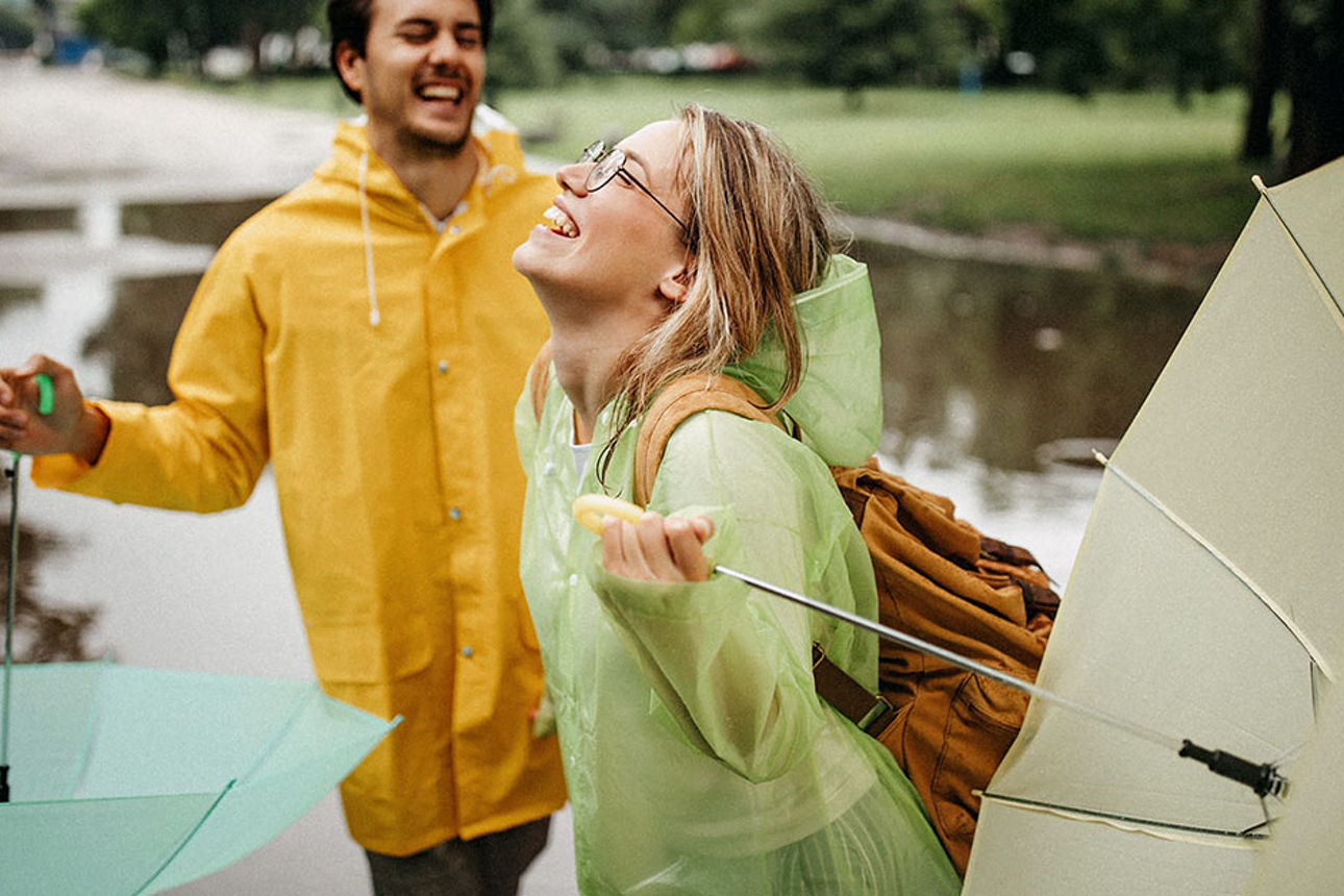 Zwei Personen sind fröhlich und halten Regenschirme in der Hand.