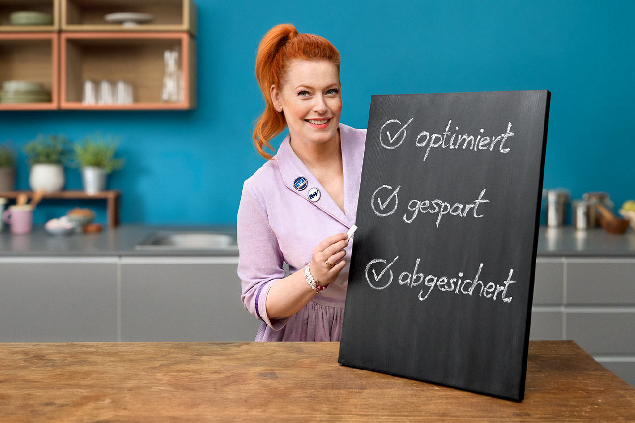 Enie van de Meiklokjes präsentiert die Vorteile des Versicherungs-Checks auf einer Kreidetafel