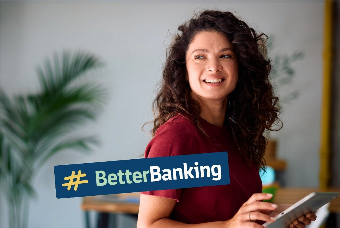 lächelnde junge Frau hält Tablet in der Hand. Aufschrift #BetterBanking.
