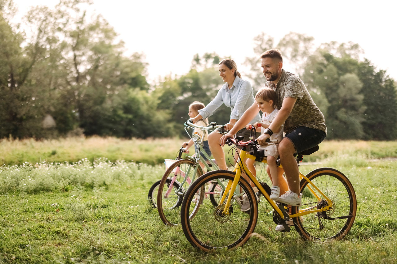 Familie radelt über das Feld bei sehr gutem Wetter und Sonnenschein.