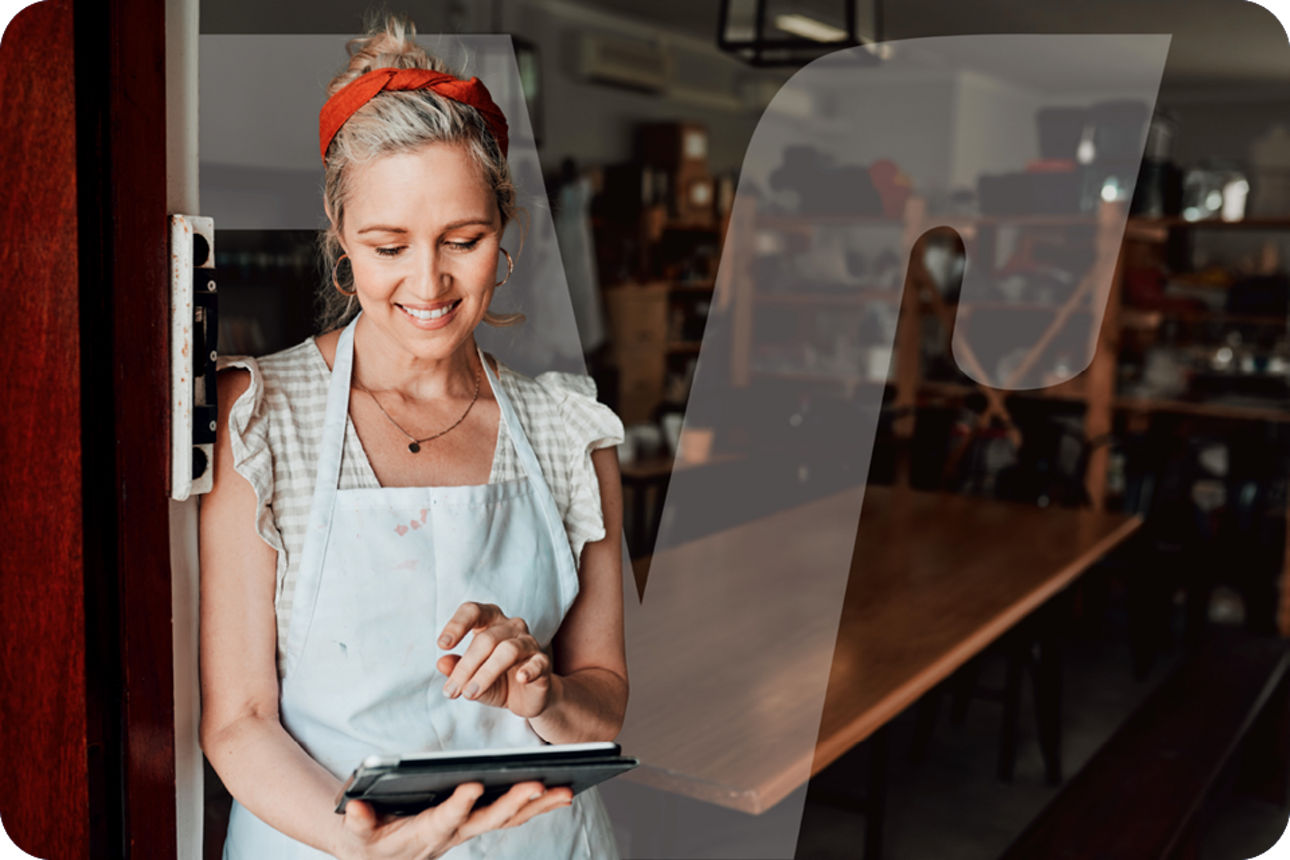Geschäftsführerin im Arbeitsraum, die eine Schürze trägt und ein Tablet in der Hand hält.