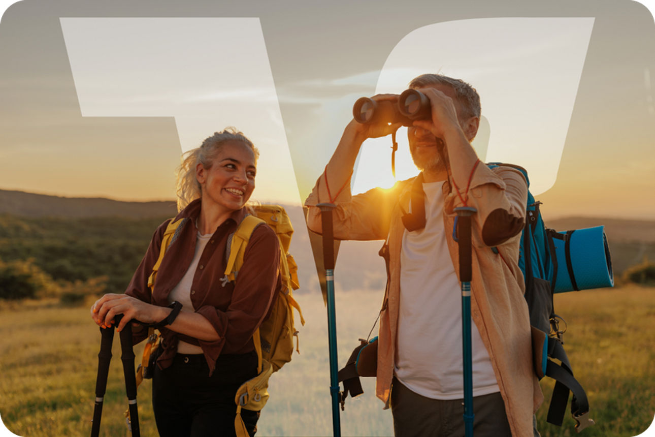 Wanderer genießen den Sonnenuntergang auf einer Wiese und beobachten die Landschaft mit Fernglas